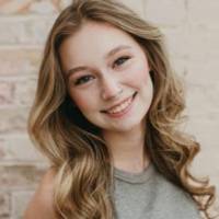 female student standing in front of a brick wall